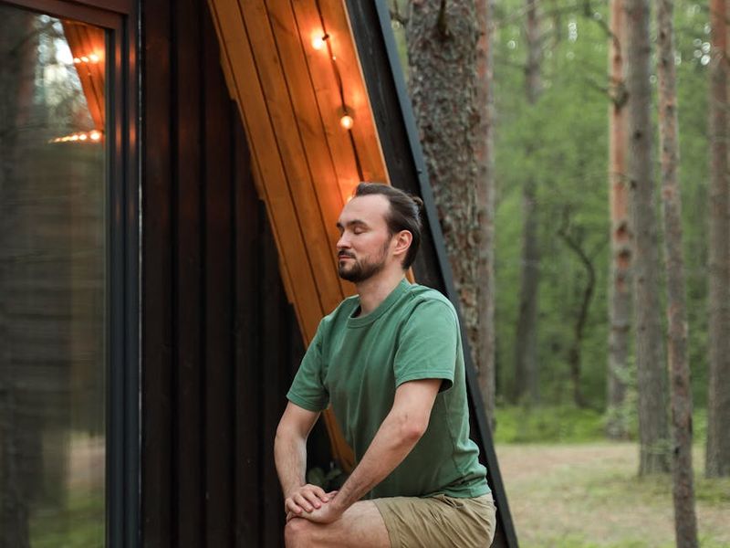 A person in a balanced yoga pose against a dark, moody background.