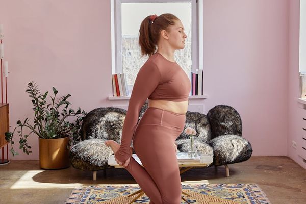 Person performing a calm, focused yoga stretch in a minimalist room.